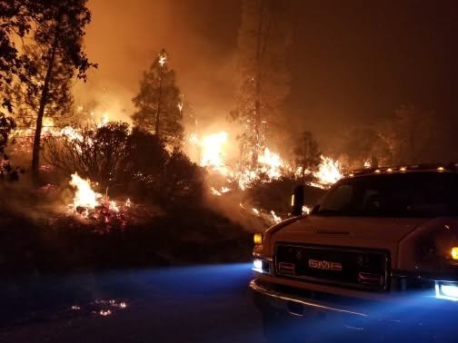 Engine working alongside a wildland fire burning at night